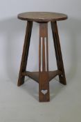 An Arts & Crafts oak occasional table, the circular top raised on three pierced splay supports