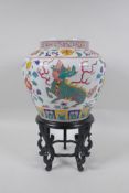 A Chinese polychrome porcelain jar decorated with kylin and lotus flowers, on a carved hardwood