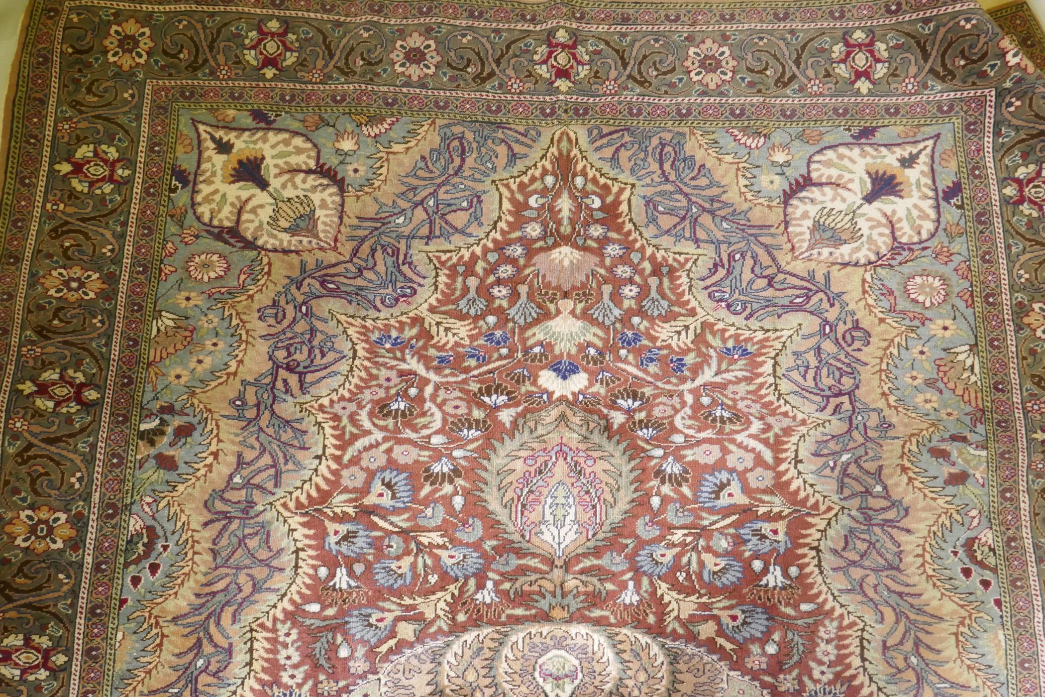 A Turkish Hereke wool carpet with central design on a faded terracotta field, with blue/grey - Image 6 of 8