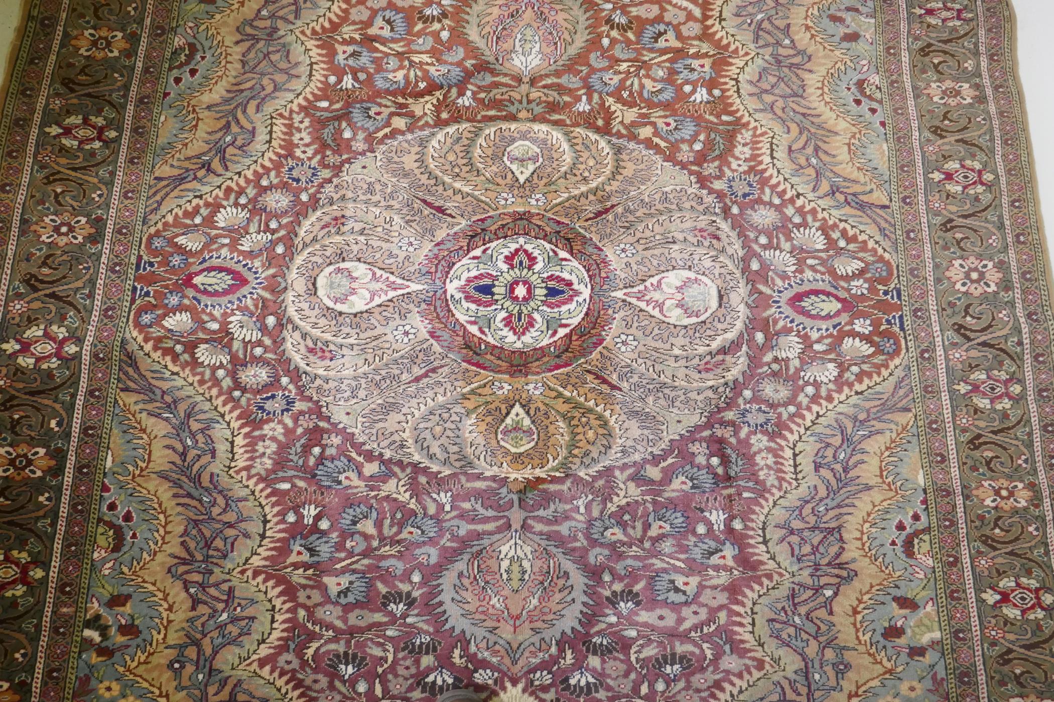 A Turkish Hereke wool carpet with central design on a faded terracotta field, with blue/grey - Image 4 of 8