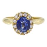 Gold oval sapphire and round brilliant cut diamond cluster ring