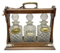 Edwardian oak tantalus with silver plated mounts with three square sided glass decanters