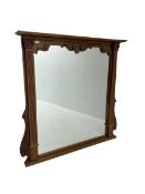 Carved and stained beech overmantle mirror with projecting cornice above square plate