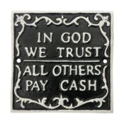 Cast iron 'In God we Trust' sign with white writing on a black ground