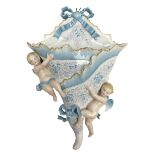 Continental wall pocket applied with two putti and ribbons and decorated with blue and gilt flowers