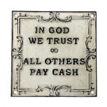 Cast iron 'In God we Trust' sign with black writing on a white ground