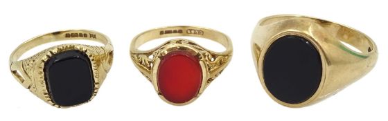 Two gold black onyx signet rings and an oval carnelian signet ring