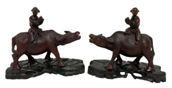Pair of Chinese hardwood figures of farmers riding water buffalo