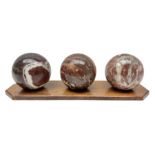 Set of three marble spheres on a elongated octagonal wooden base