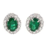 Pair of white gold oval cut emerald and round brilliant cut diamond cluster stud earrings