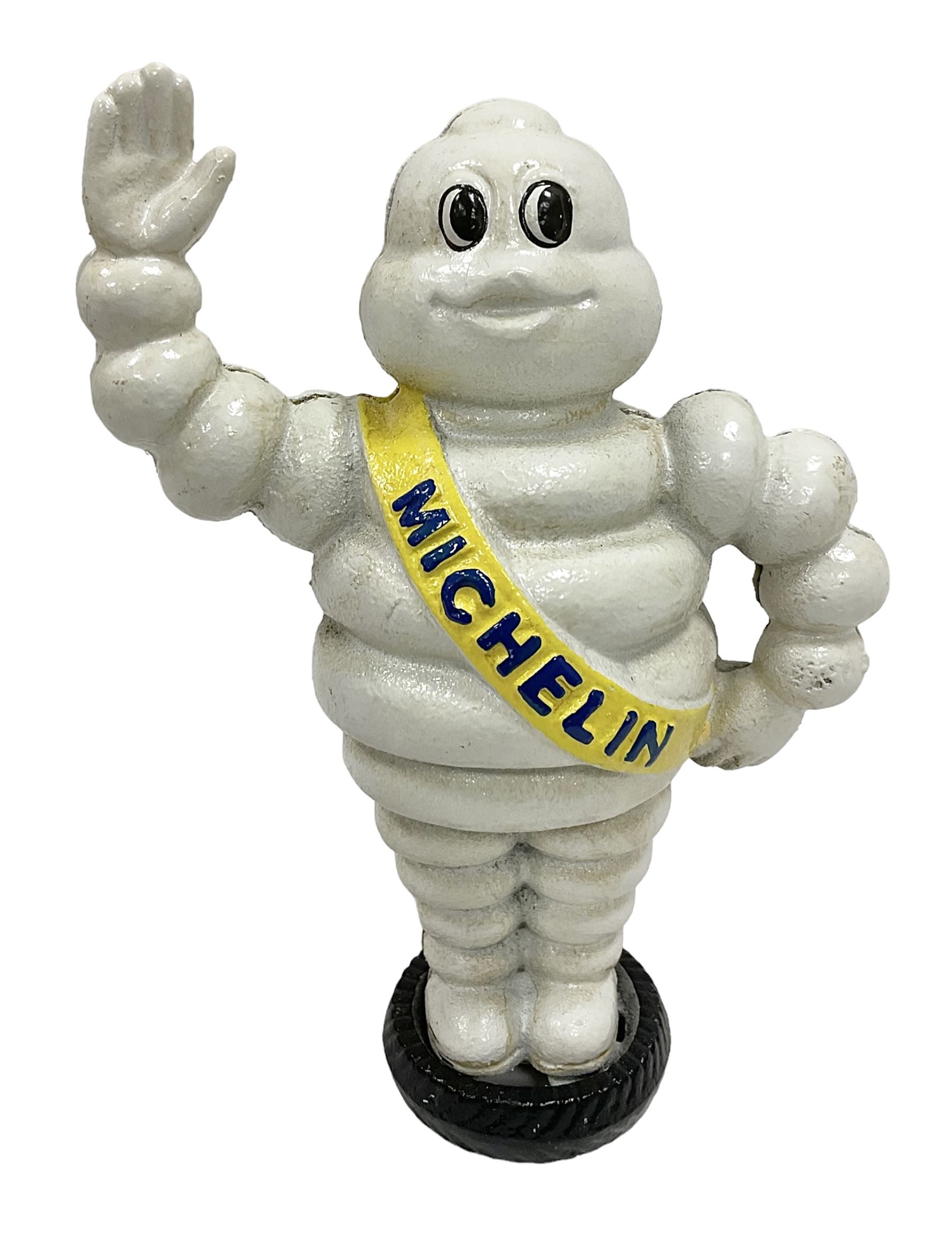 Cast iron money bank of a waving Michelin man stood on a tyre