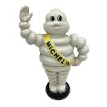 Cast iron money bank of a waving Michelin man stood on a tyre