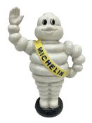 Cast iron money bank of a waving Michelin man stood on a tyre