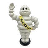 Cast iron money bank of a waving Michelin man stood on a tyre