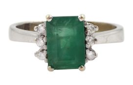 White gold emerald ring set with three round brilliant cut diamonds either side