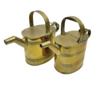 Set of two graduating brass watering cans
