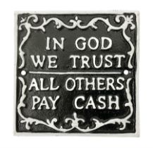 Cast iron 'In God we Trust' sign with white writing on a black ground