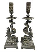 Pair of late 19th/ early 20th century brass candlesticks in the form of dolphins upon a stepped base