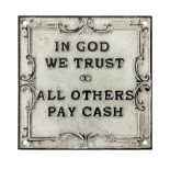 Cast iron 'In God we Trust' sign with black writing on a white ground