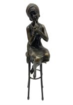 Art Deco style bronze figure of a lady seated on a stool applying lipstick