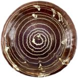 A 19th century circular slipware dish with spiral comb decoration.