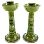 A pair of Ewenny green glazed pottery candlesticks.