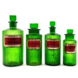 Four green glass apothecary jars and stoppers.