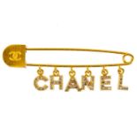 A Chanel gold tone pin brooch with crystal set charm logo.