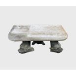 A garden bench, a marble slab raised on three composition stone dolphin supports. Width 91cm.