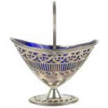 A George III Irish silver pedestal swing-handled sugar basket with a blue glass insert.