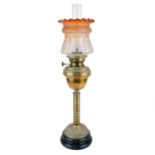 A Victorian brass oil lamp with a brass oil reservoir and an etched orange glass shade.