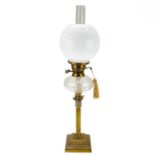 A Victorian brass oil lamp with a clear glass oil reservoir and white glass shade.