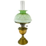 A Victorian brass oil lamp with a moulded green glass shade.