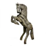 A large wood carved sculpture of a free standing rearing horse.