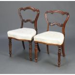 A pair of Victorian carved rosewood spoon back chairs with shaped mid rails and overstuffed seats,