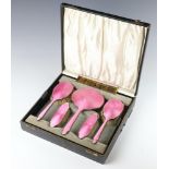 An Art Deco silver and pink guilloche enamel dressing table set comprising hand mirror, 2 hair