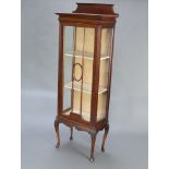 An Edwardian mahogany display cabinet with raised back, the shelved interior enclosed by a