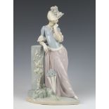 A Lladro figure of a lady standing beside a wall holding a parasol 36cm