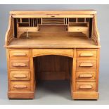 A 19th/20th Century oak roll top kneehole pedestal desk with tambour shutting revealing a well