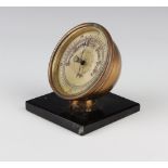 A 1930's aneroid desk barometer with 7cm circular silvered dial contained in a gilt metal case and