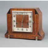 An Art Deco chiming mantel clock with square silvered dial and Arabic numerals contained in a walnut