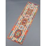 A faded green, white and brown ground Chobi Kilim runner with stylised diamonds to the centre