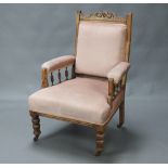 A Victorian carved bleached mahogany showframe armchair with bobbin turned decoration, raised on