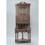 A Victorian heavily carved oak corner cabinet, the upper section with shaped cornice fitted