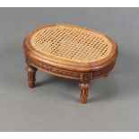 An Edwardian oval carved walnut footstool with woven cane panel to the centre raised on turned and