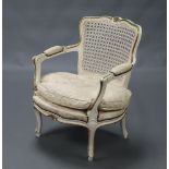 A 1950's white painted French open arm salon chair with woven cane seat and upholstered cushion,