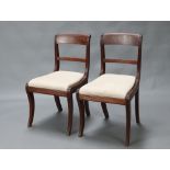 A pair of 19th Century mahogany bar back dining chairs with drop in seats, raised on sabre