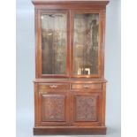 A Victorian carved mahogany bookcase on cabinet, the upper section with moulded cornice, interior