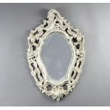A shaped plate mirror contained in a carved wood and white painted plaster frame 62cm x 39cm Some