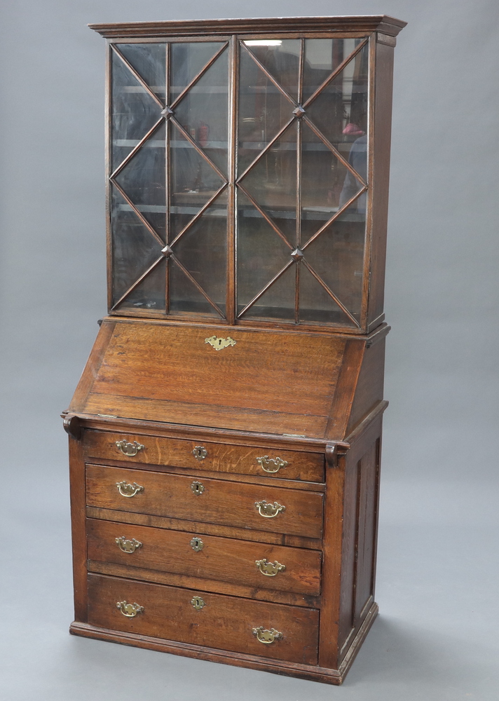 A 19th Century oak bureau bookcase the later associated top fitted shelves enclosed by astragal